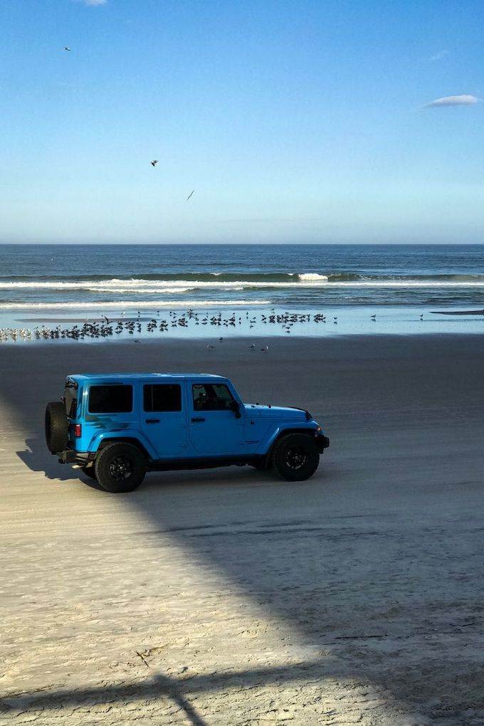 Blue truck driving on the sand of Daytona Beach.