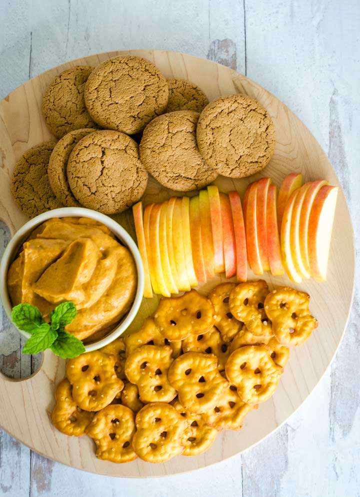 Ginger snaps, apple slices, pretzels, cream cheese dip on board