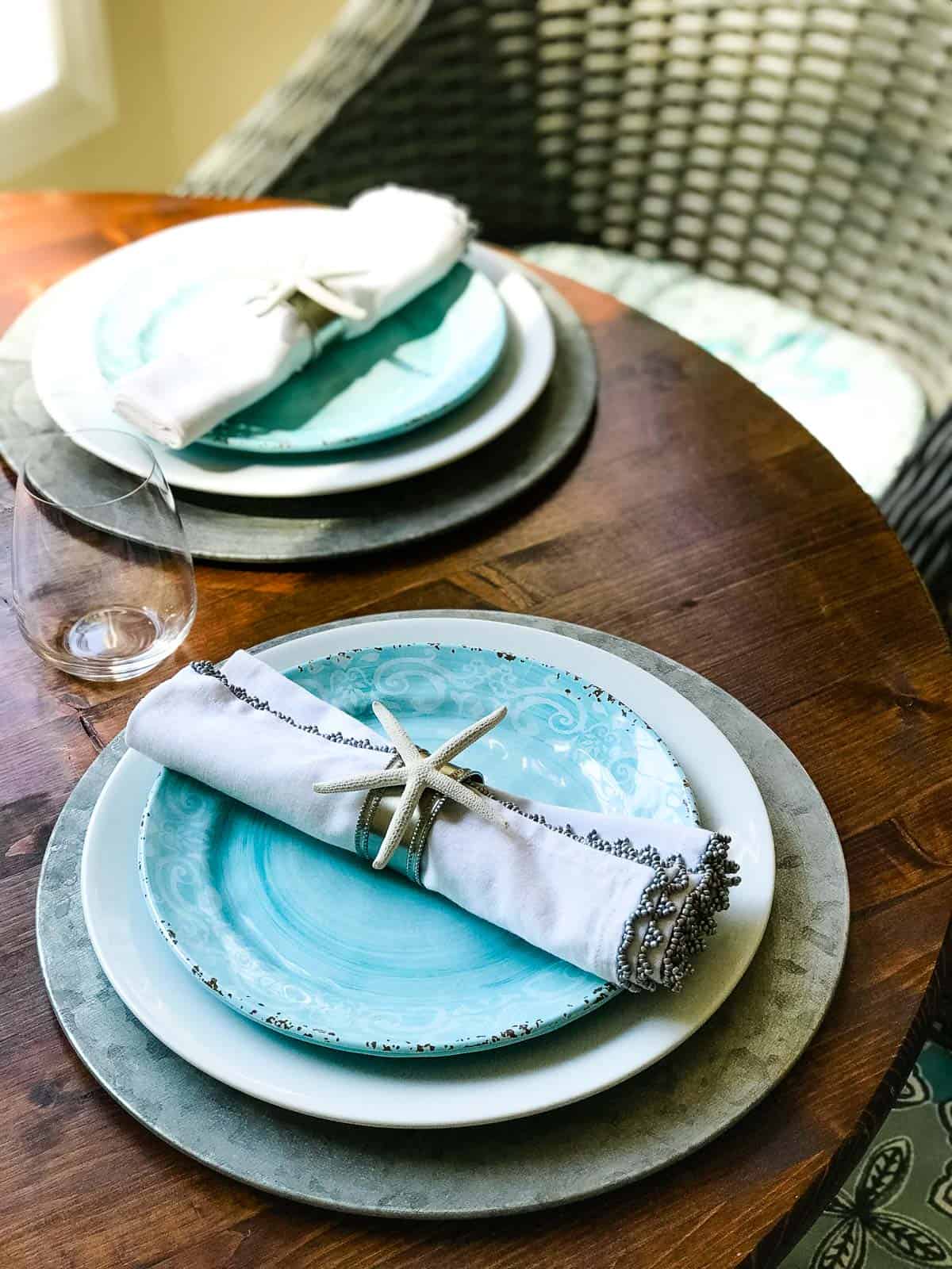 Coastal place settings on wood table with wicker chair