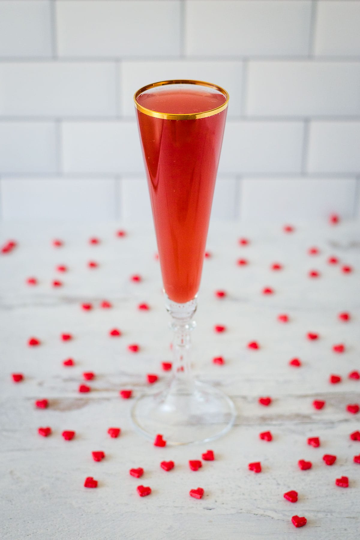 Pomegranate mimosa in gold rimmed flute with red candy hearts.