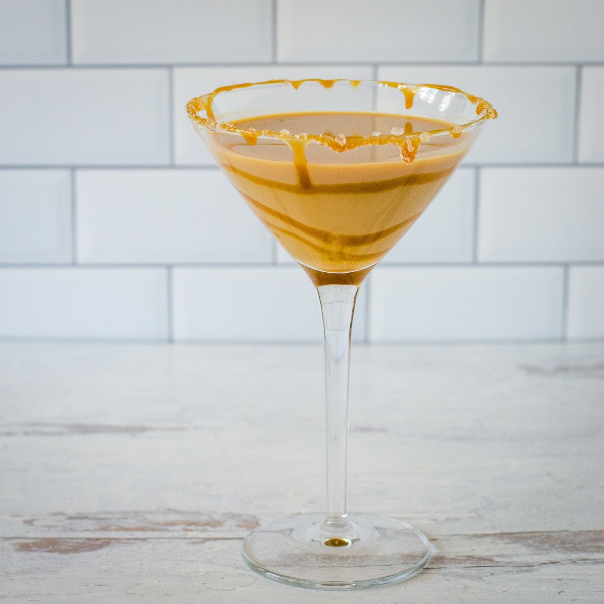 Salted caramel martini in a cocktail glass with caramel drizzle and sea salt.