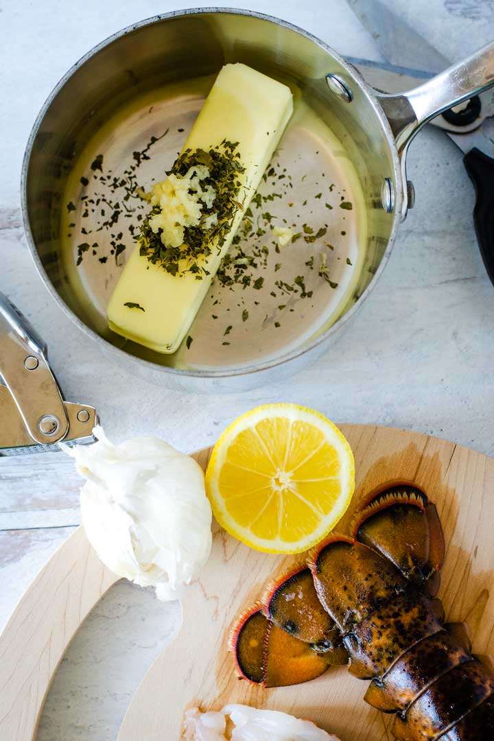 Sauce pan with butter, herbs, garlic, lemon, lobster tail