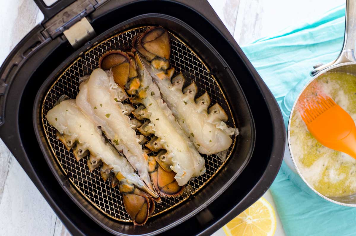 Split raw lobster tails in air fryer basket