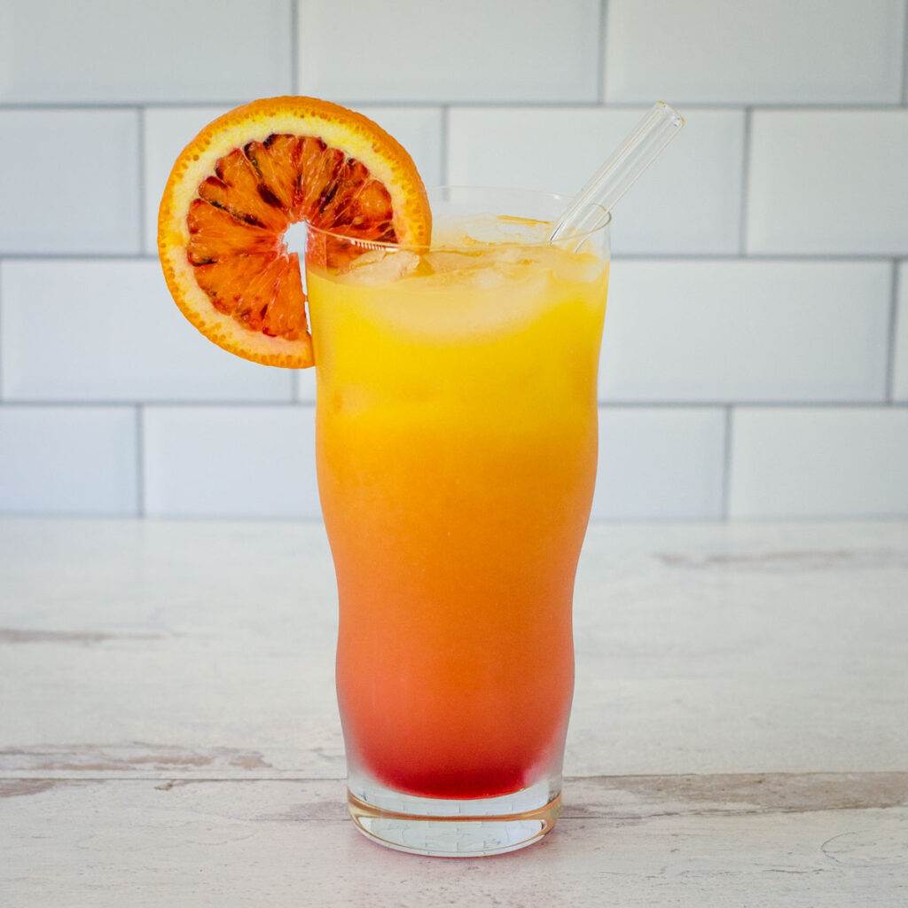 Vodka sunrise with orange slice and glass straw