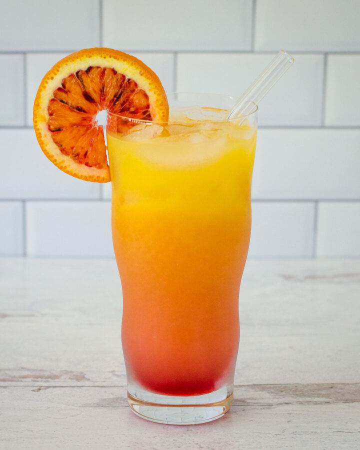 Vodka sunrise with orange slice and glass straw