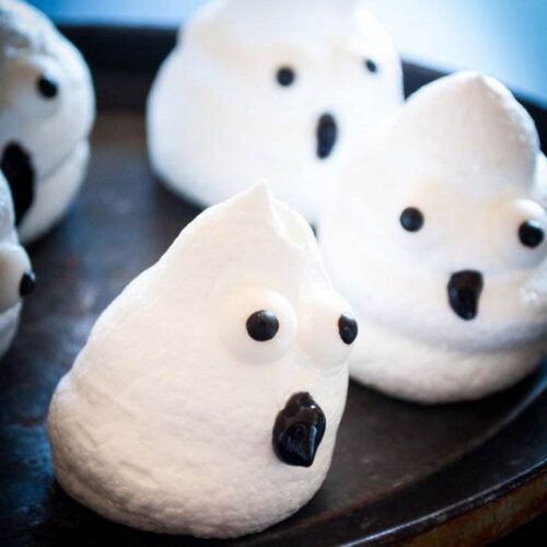 Meringue ghost cookies on black plate.