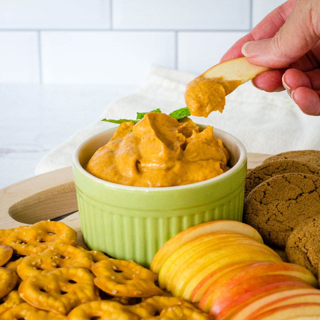 Dipping apple slice into pumpkin cream cheese dip