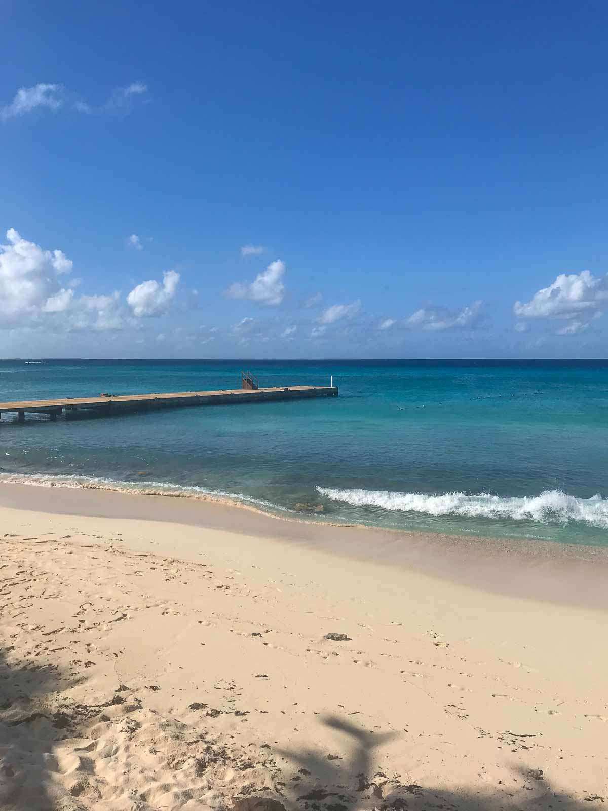 Sandy beach with turquoise water and long dock