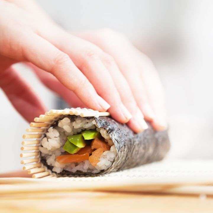 Rolling nori, rice and fillings in bamboo mat