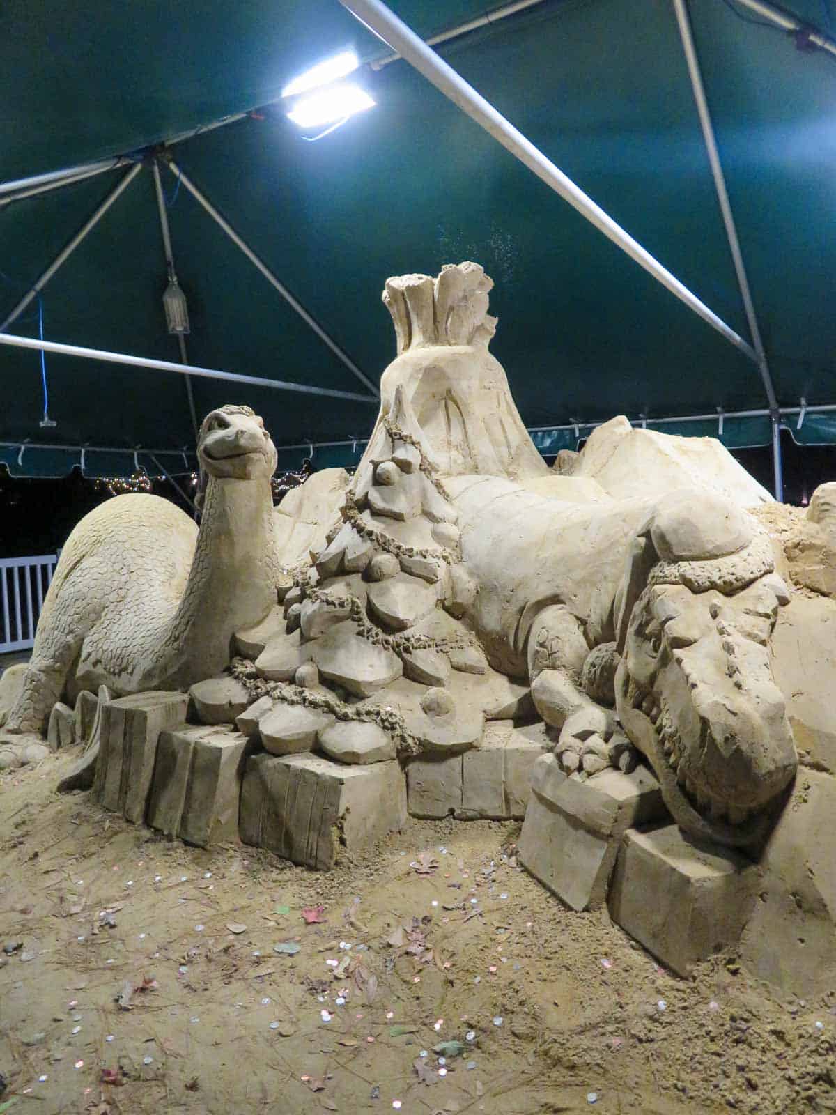Giant sand sculpture with Christmas tree, alligator, dinosaur