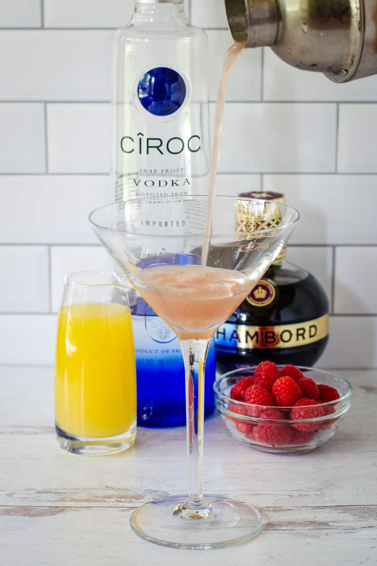 Pouring French martini into cocktail glass, ingredients in background