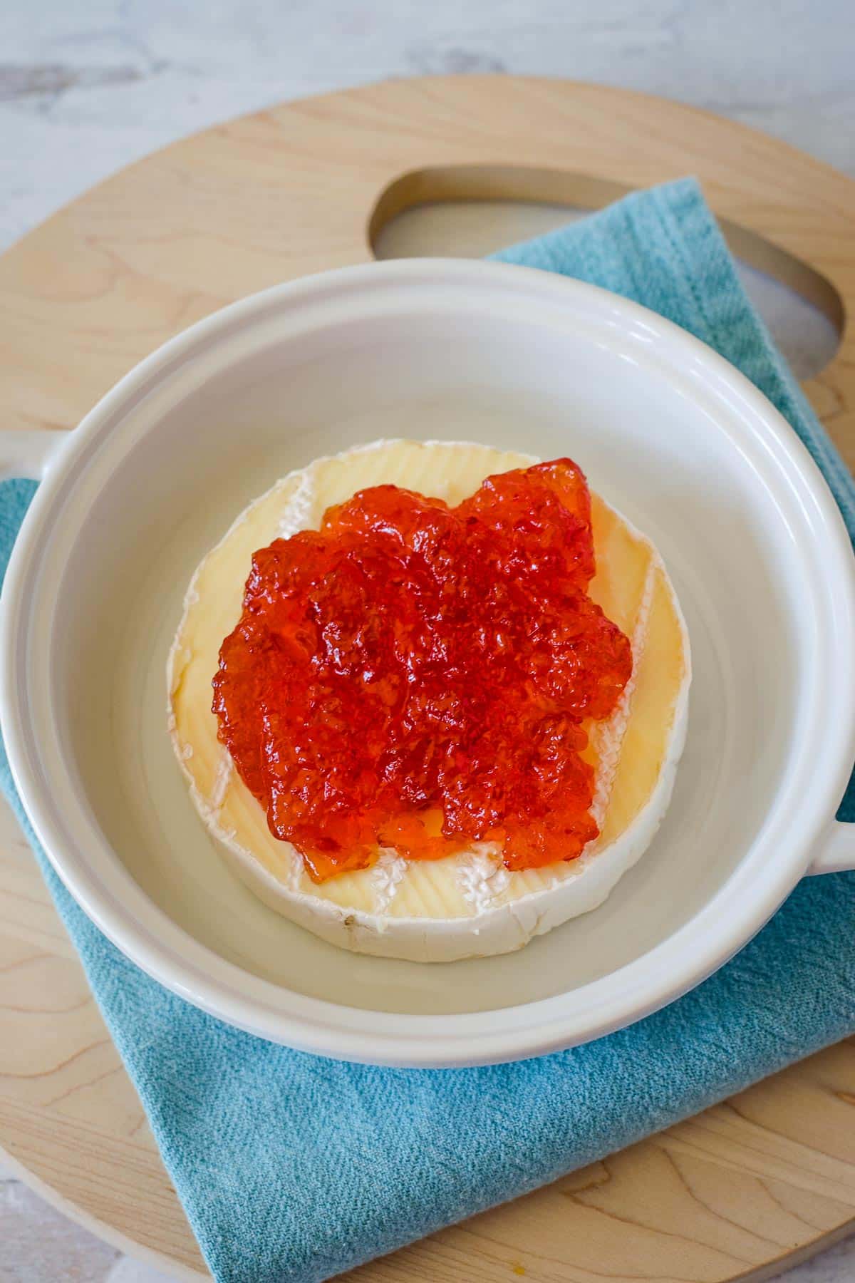 Brie topped with red pepper jelly in baking dish