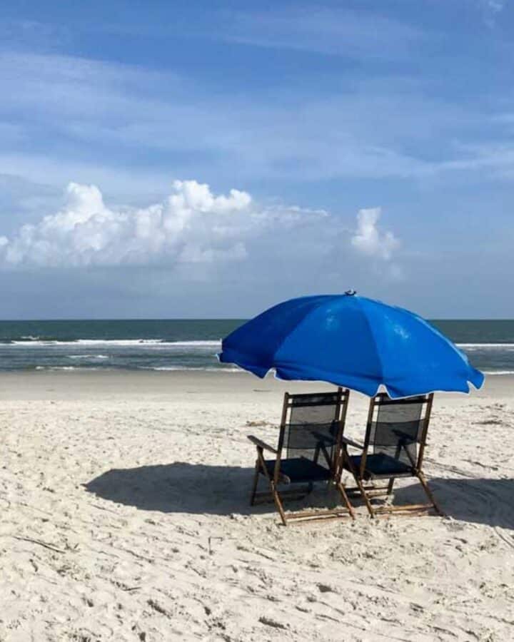 Beach with chairs and blue umbrella
