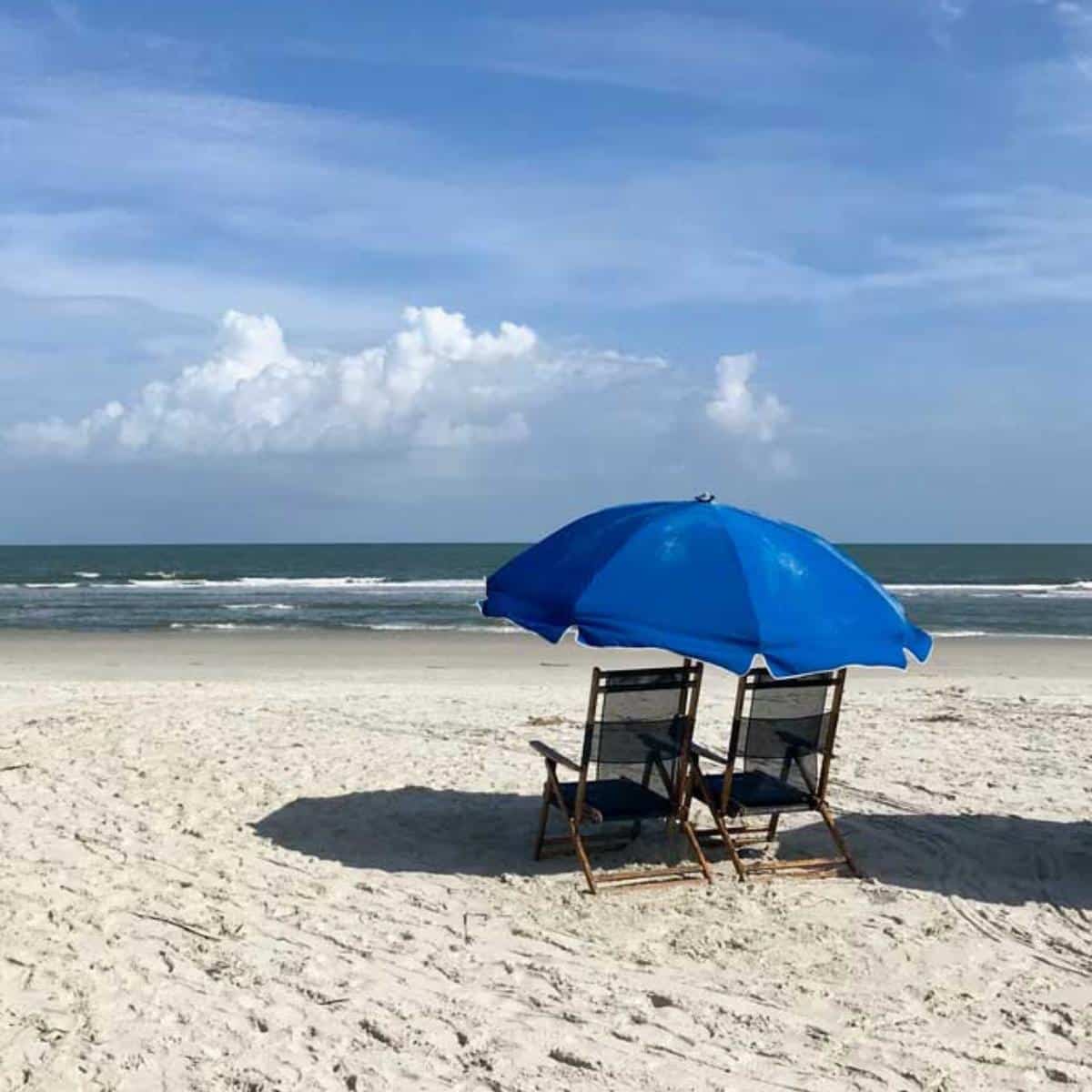 Beach with chairs and blue umbrella
