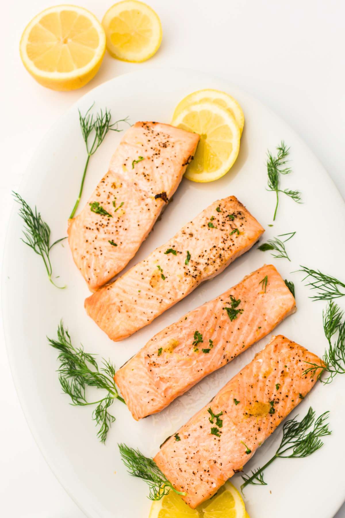 Salmon filets with lemon on white platter.