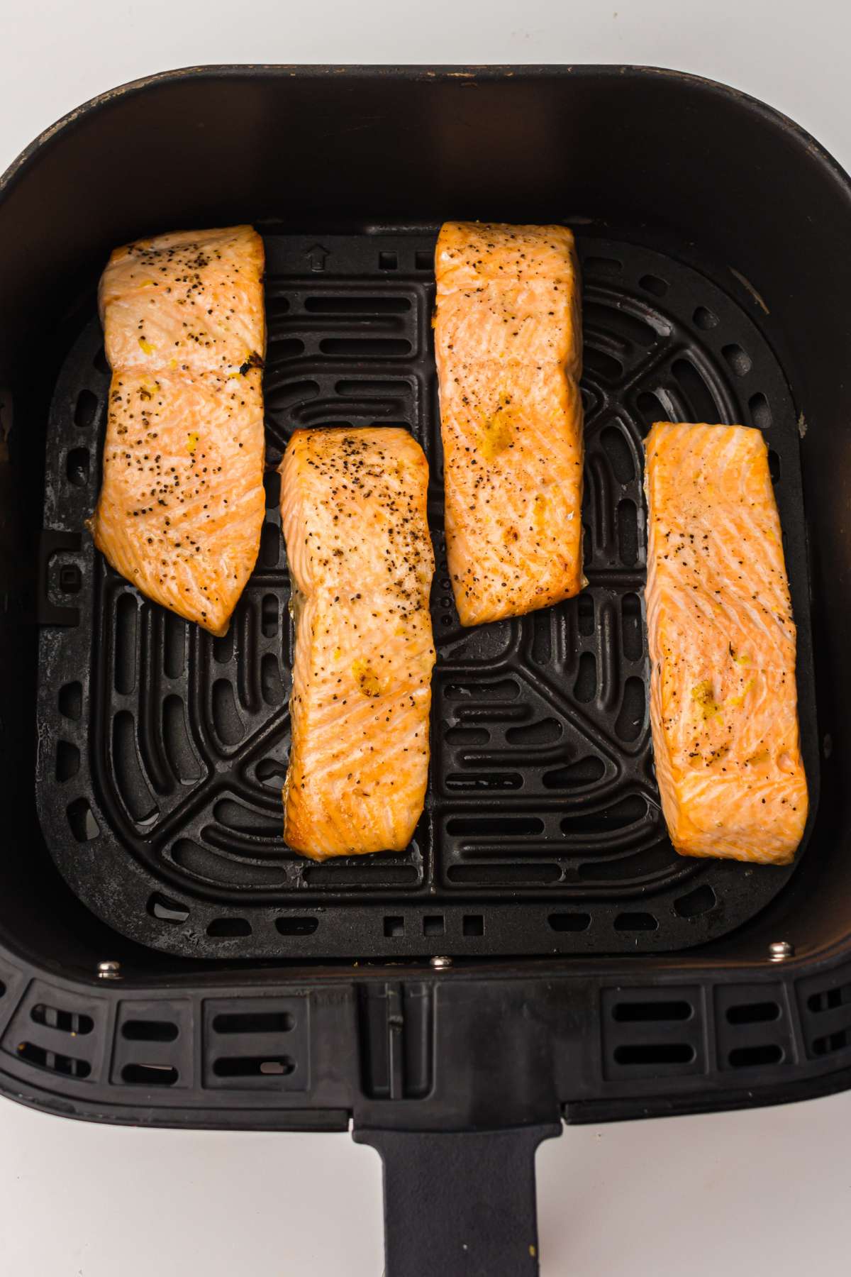 Coked salmon in air fryer basket.