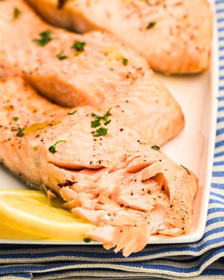 Flaked salmon filets with lemon on plate.