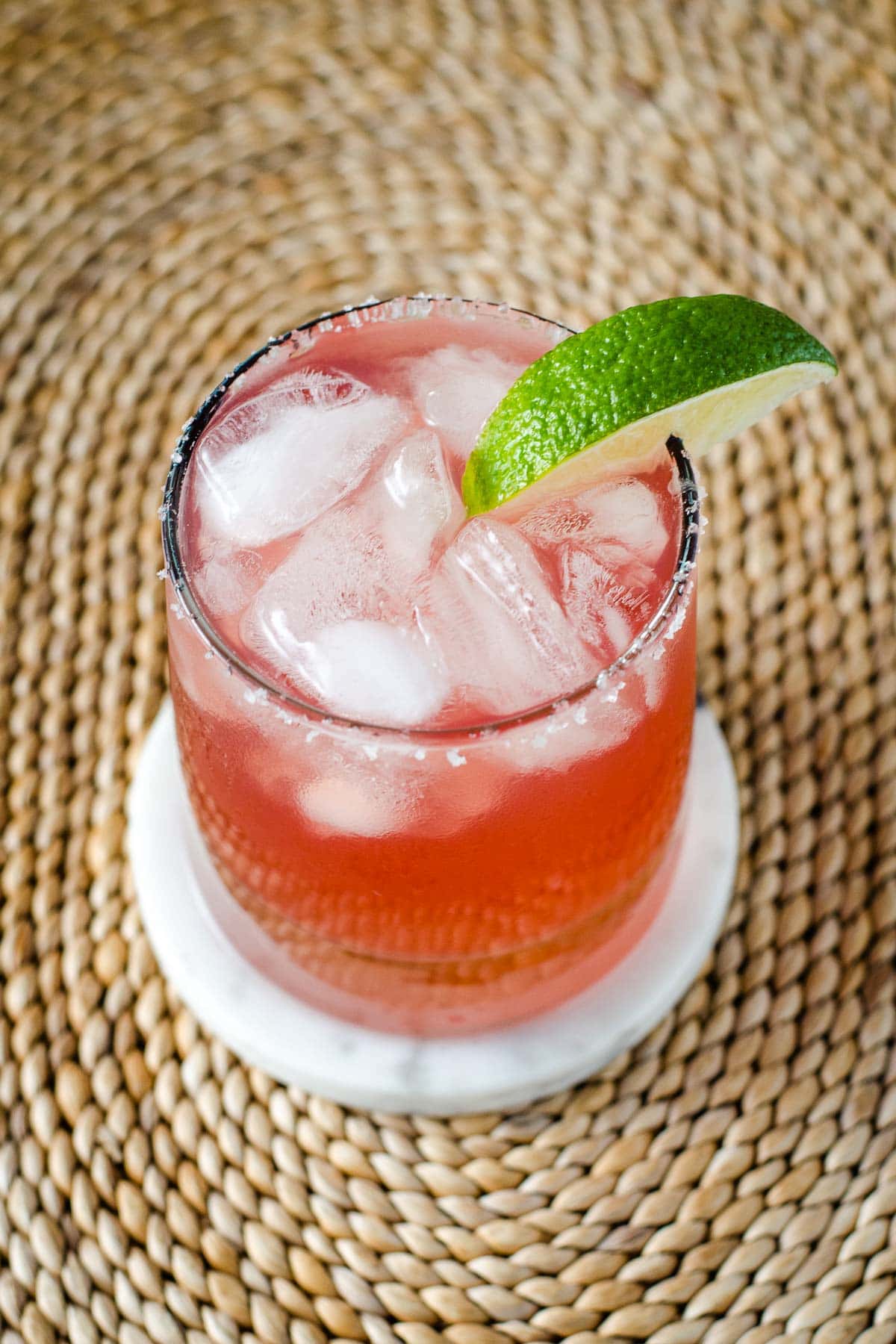 Cranberry margarita with salted rim and lime wedge.