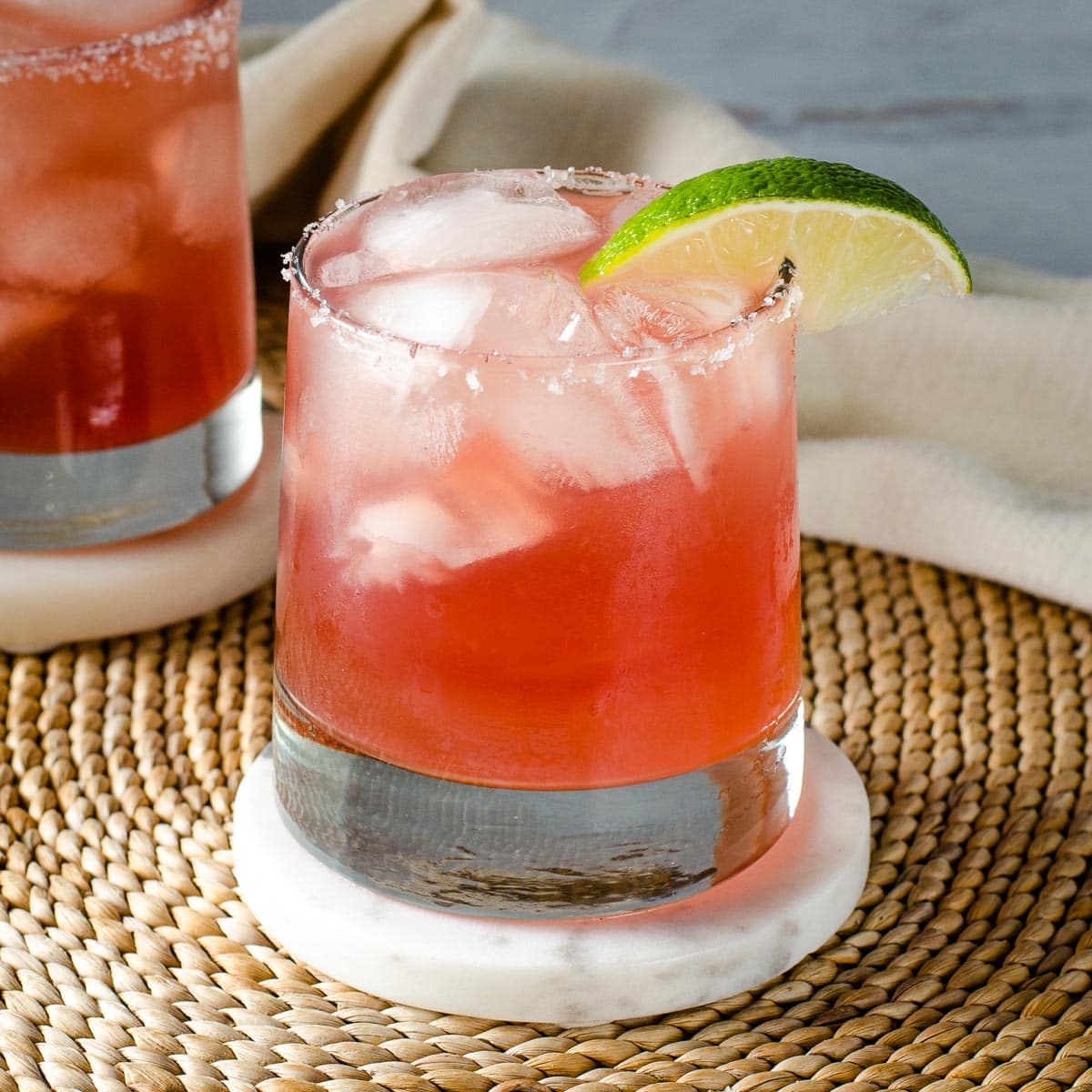 Cranberry margarita with salted rim and lime wedge.