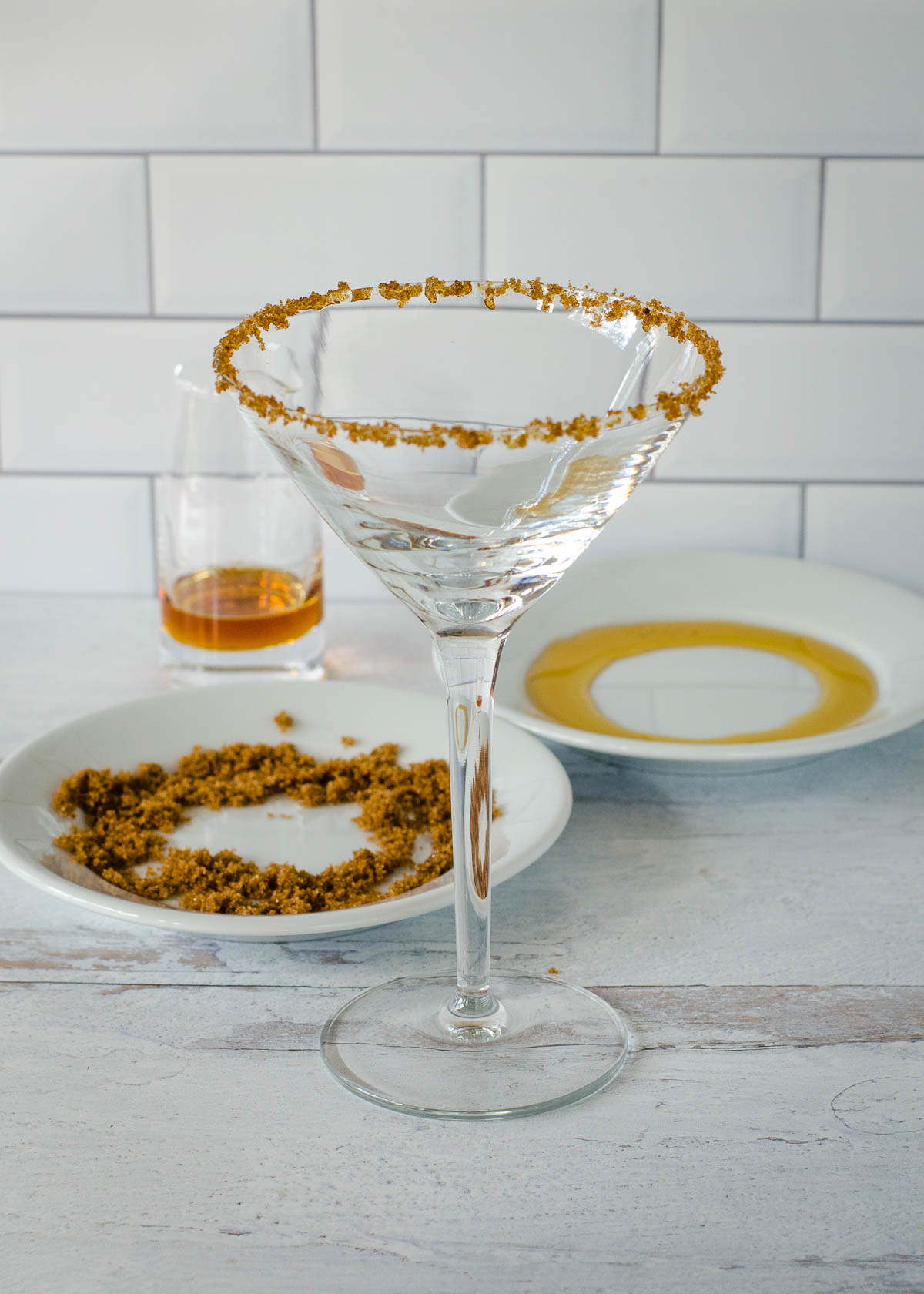 Sugar rimmed cocktail glass, plates with brown sugar and maple syrup and small glass pitcher of syrup.