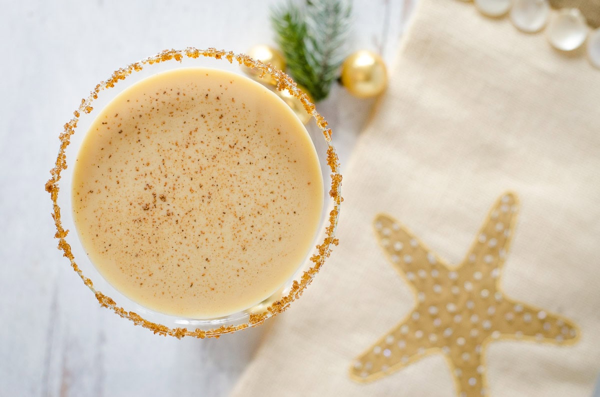 Overhead view of eggnog cocktail with Christmas decor.