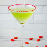 Grinch martini with red sugar rim and red candies.