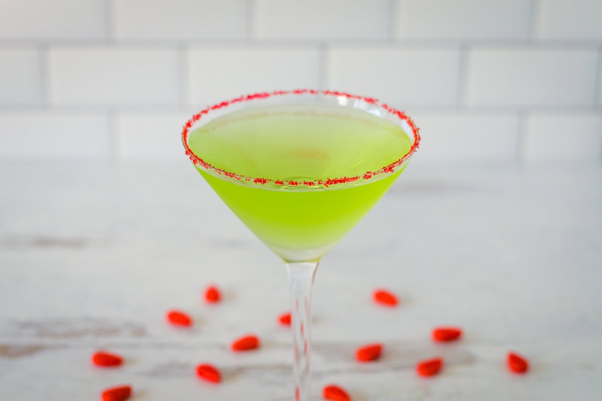 Grinch martini with red sugar rim and red candies.