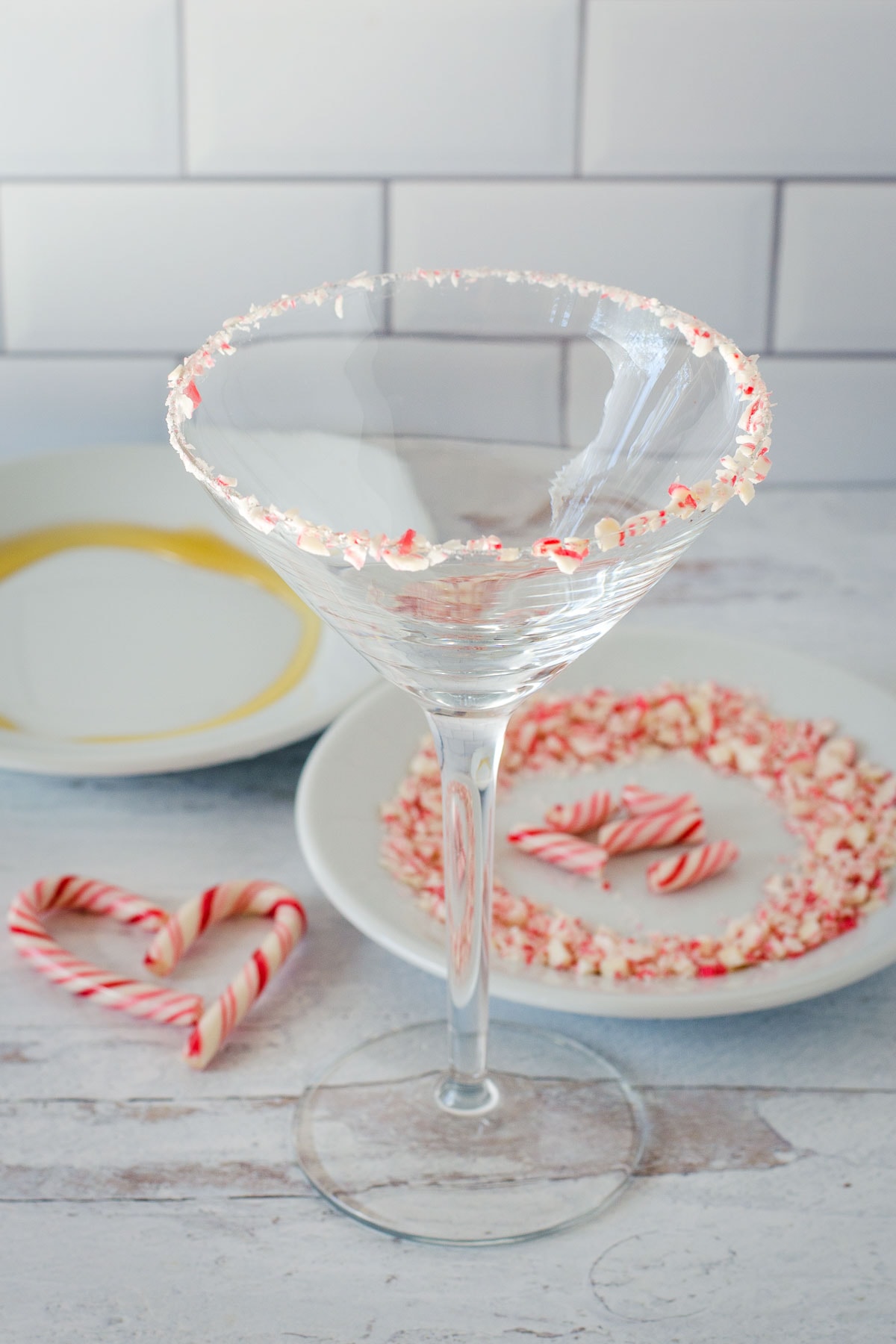 Martini glass with crushed candy rim, plate with honey, plate with candy cane piece and candy cane heart.