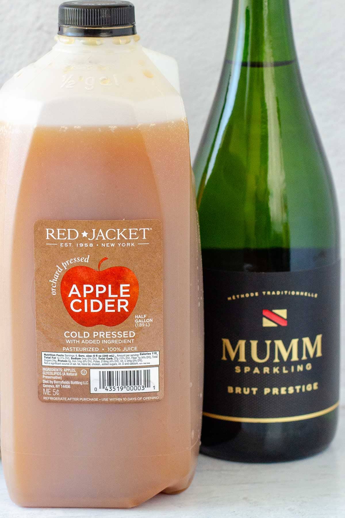 Jug of apple cider next to bottle of champagne.