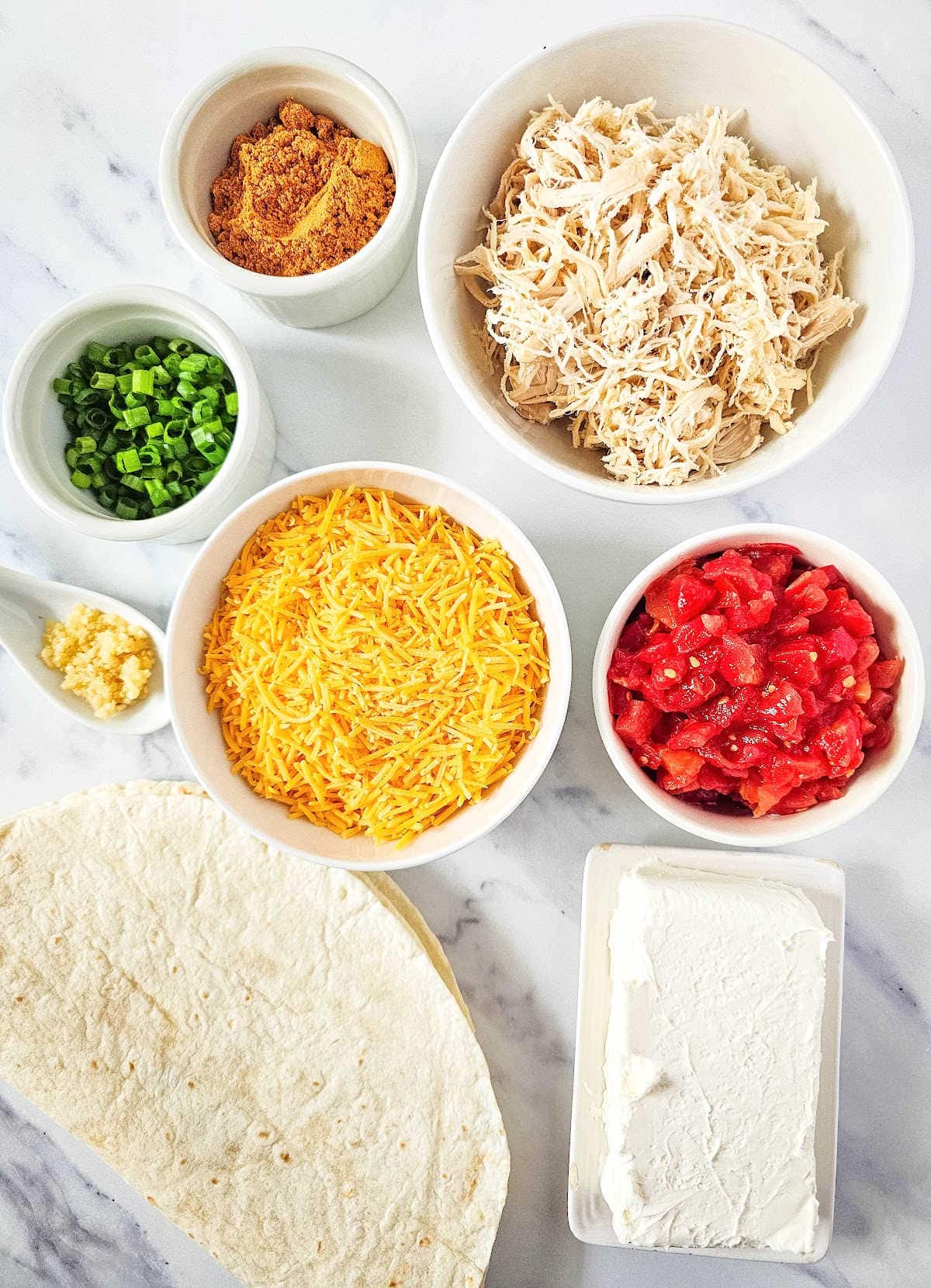 Taco pinwheel ingredients including tortilla, cheese, vegetables and shredded chicken.