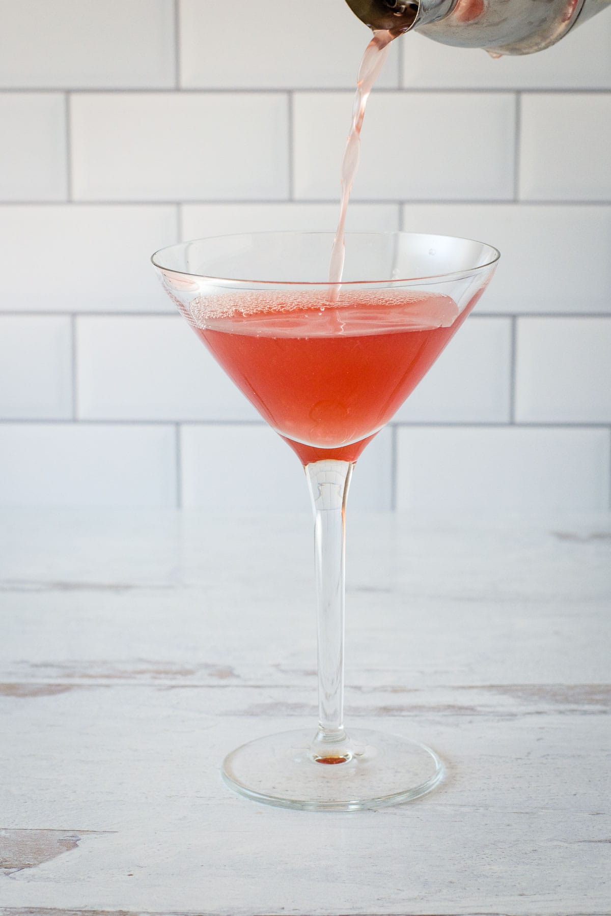 Pouring cranberry martini into glass.