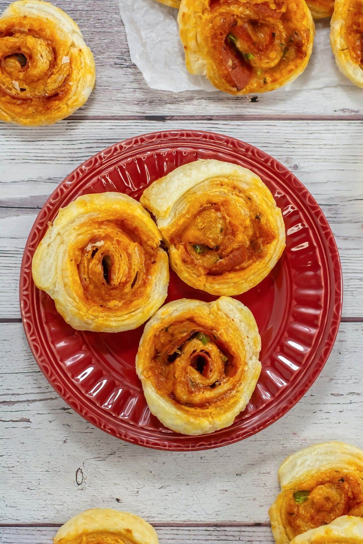 Pizza pinwheels on red plate and table.