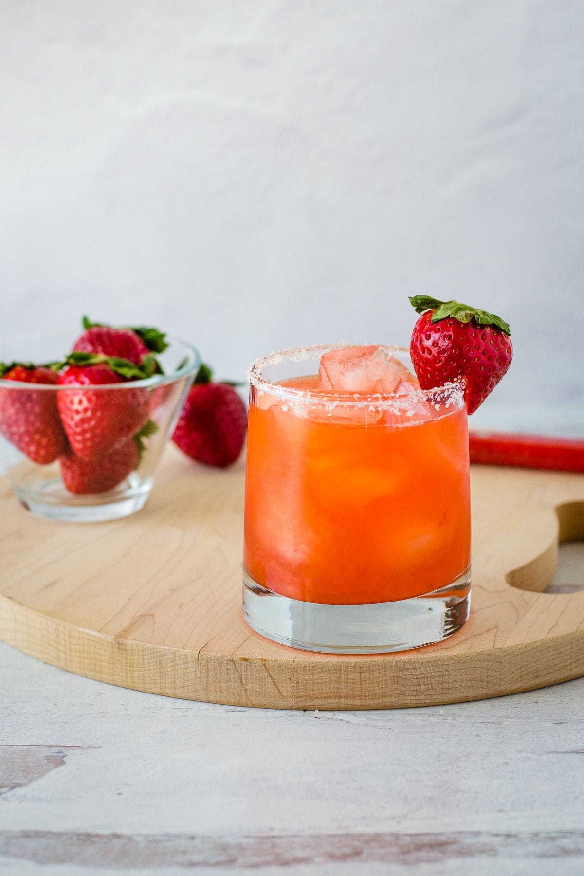 Strawberry margarita with strawberries on cutting board.