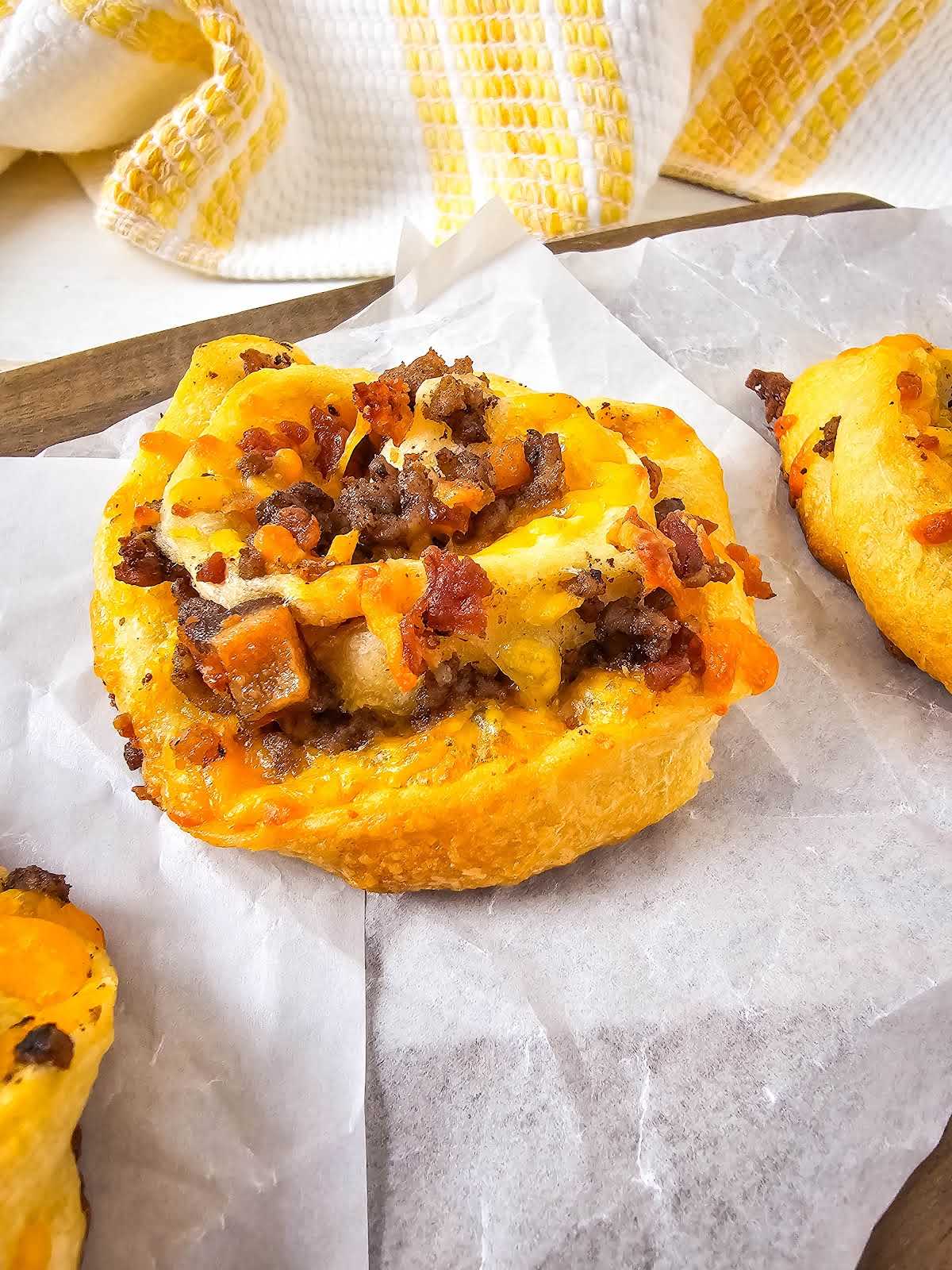 Bacon cheeseburger pinwheels on parchment paper.