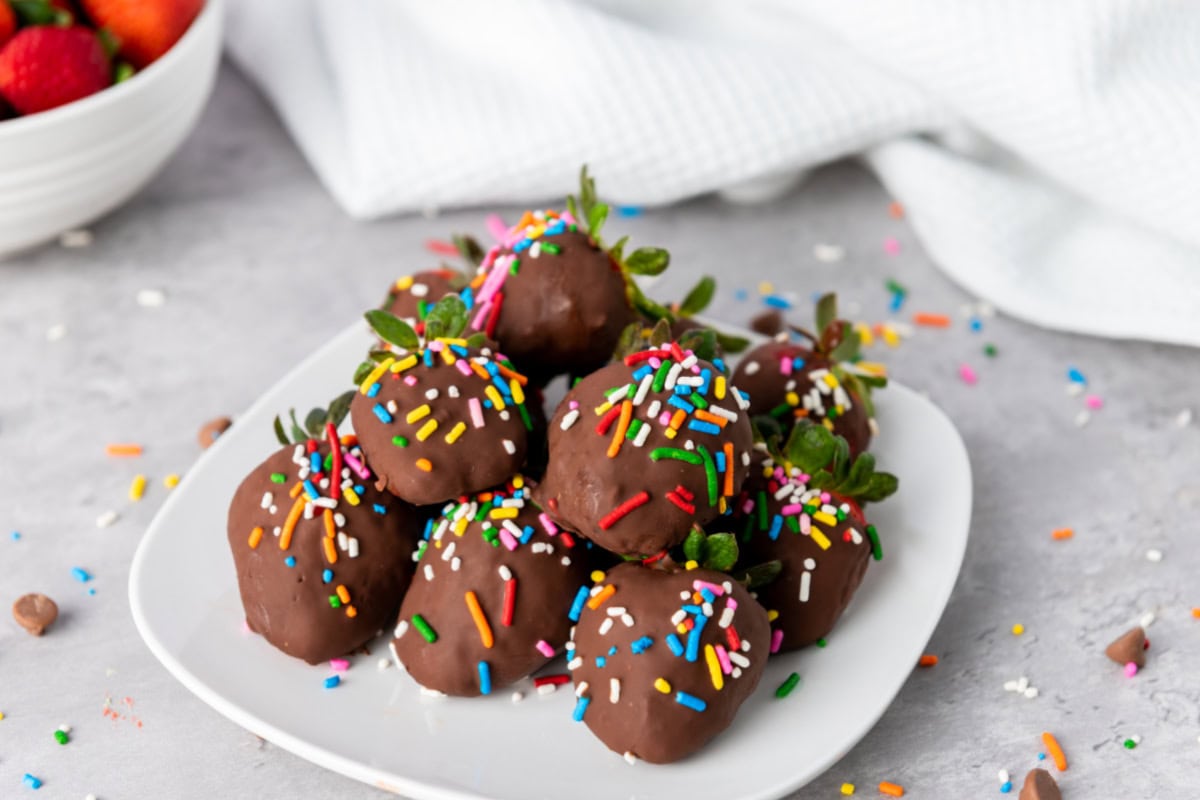 Chocolate covered strawberries on white plate.