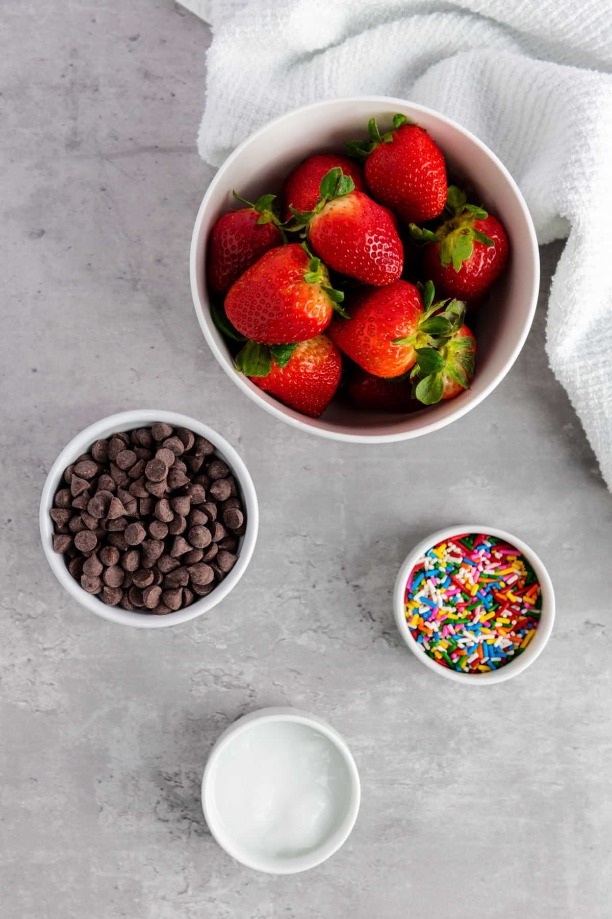 Bowls of strawberries, chocolate chips, sprinkles  and coconut oil.