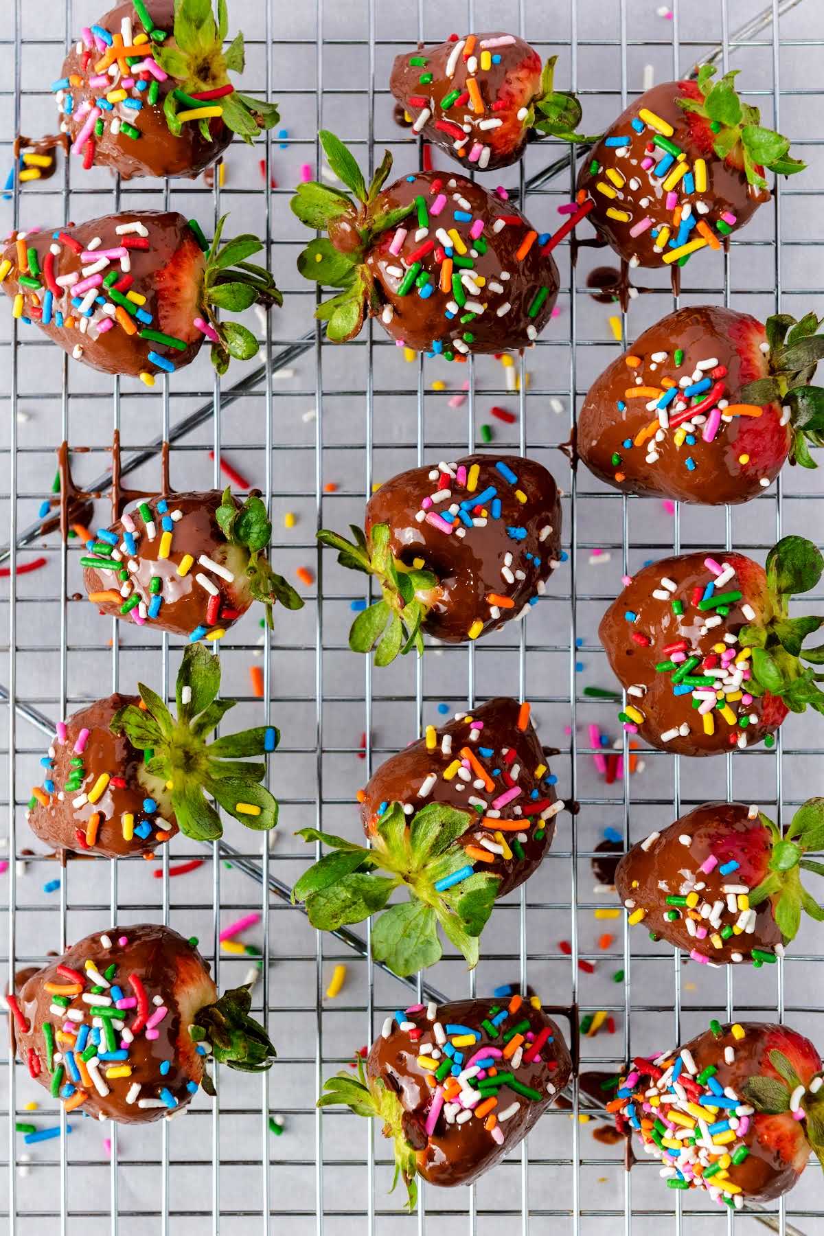 Chocolate covered strawberries with sprinkles on wire rack.