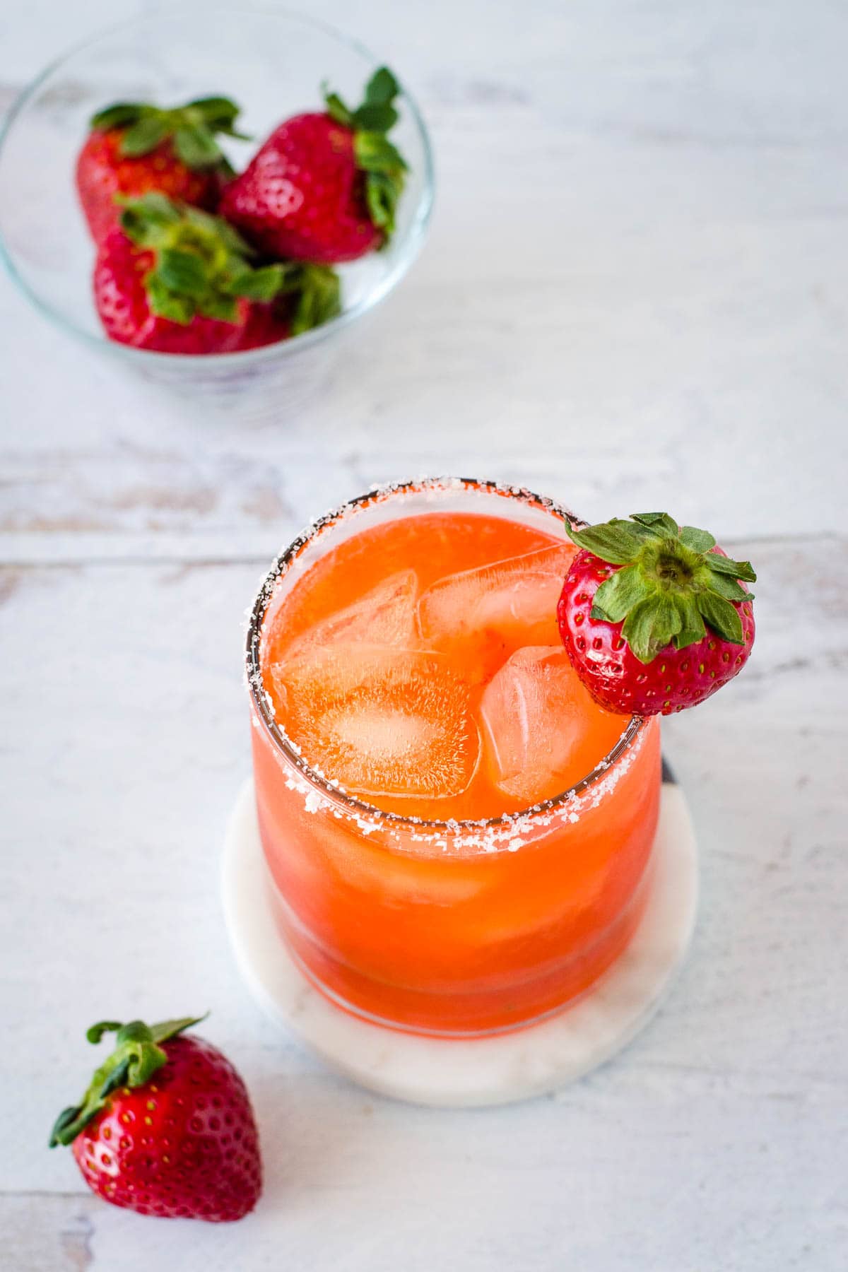 Strawberry margarita with bowl of strawberries.