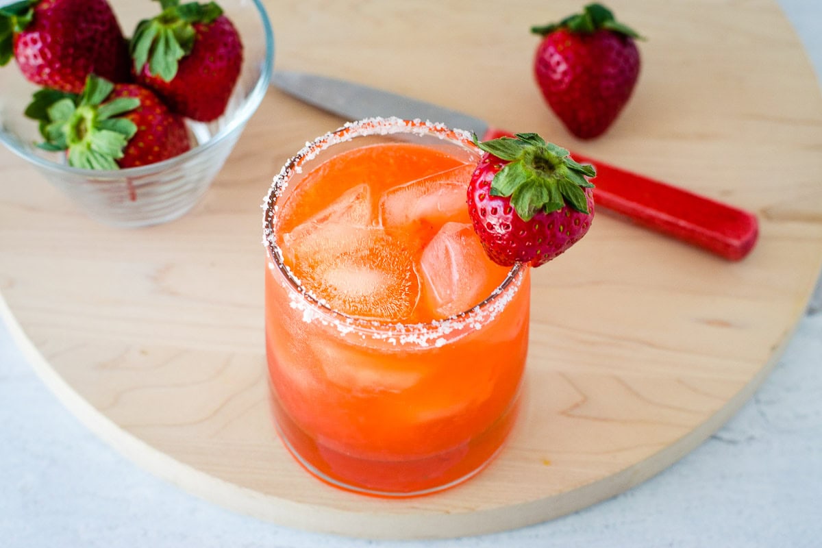 Strawberry margarita with strawberries on cutting board.