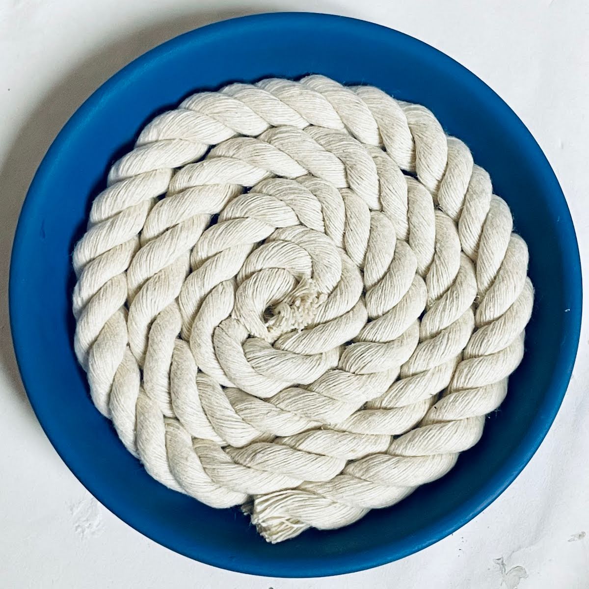 DIY coaster with dark blue clay base and rope inset.