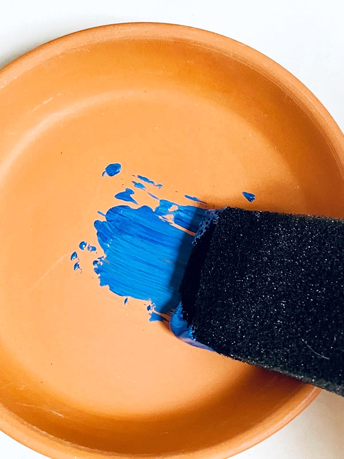 Painting clay saucer blue.