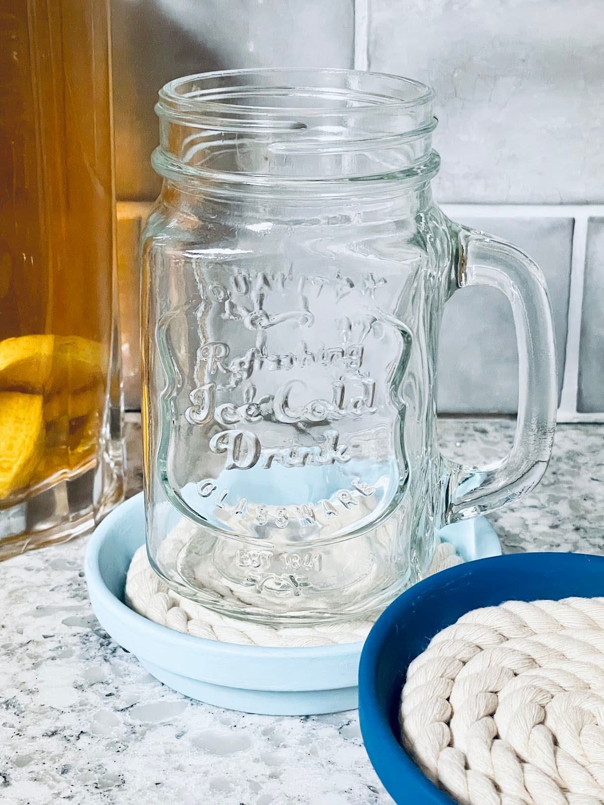DIY coasters painted in shades of blue, with a mason jar mug on one coaster.