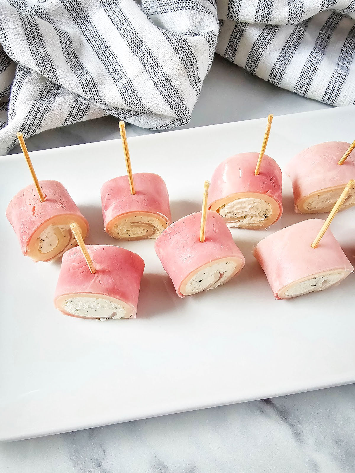 Ham cream cheese roll ups with toothpicks on plate.