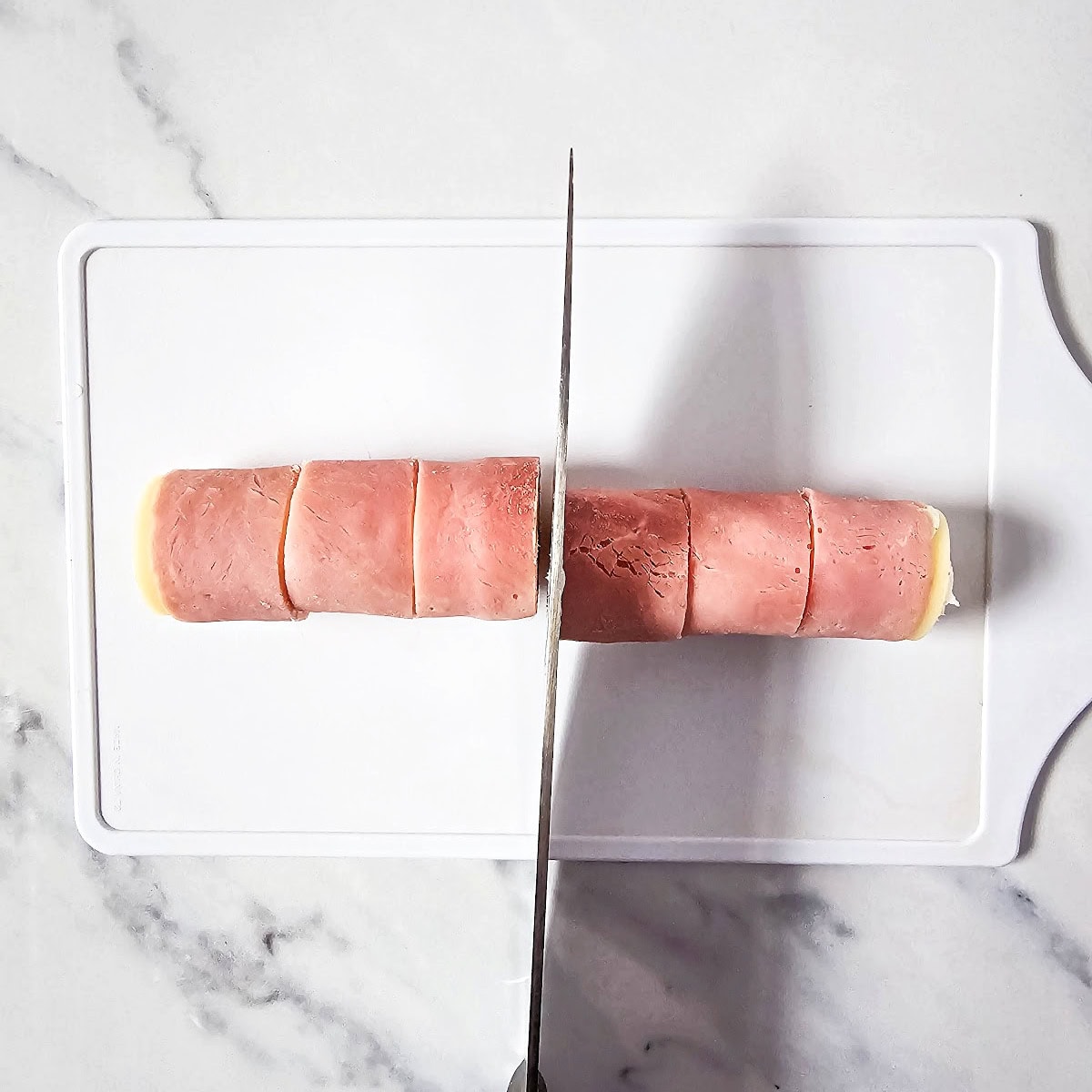 Knife slicing roll into six pieces.