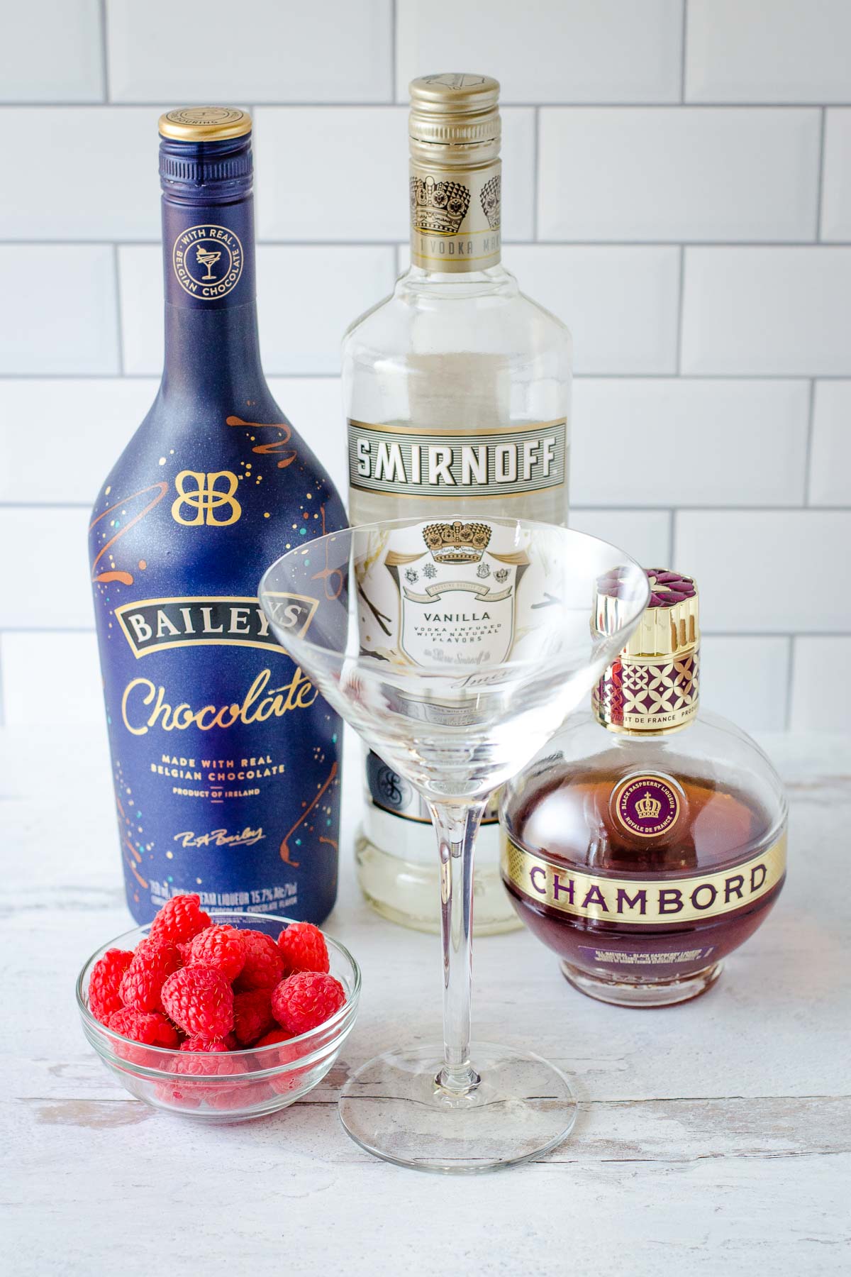 Fresh raspberries in small bowl, cocktail glass, Baileys Chocolate, vanilla vodka and Chambord.