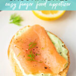 Smoked salmon crostini bite on white plate with dill and lemon.