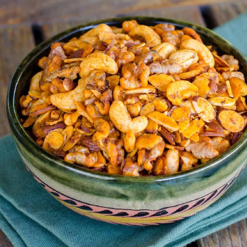 Snack mix with nuts in green bowl.