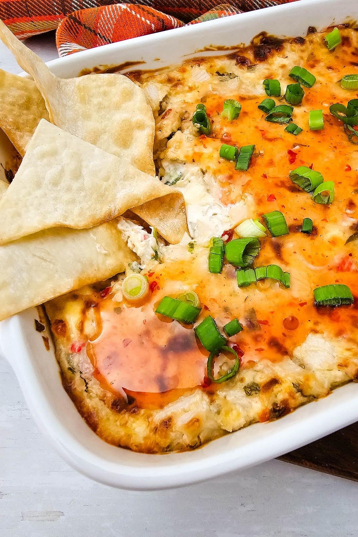 Close up of hot crab dip with chips in baking dish.