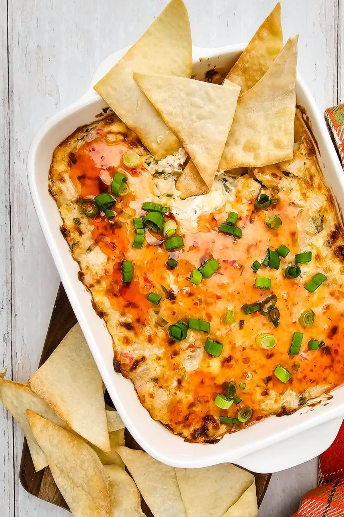 Crab rangoon dip with wonton chips in white baking dish.
