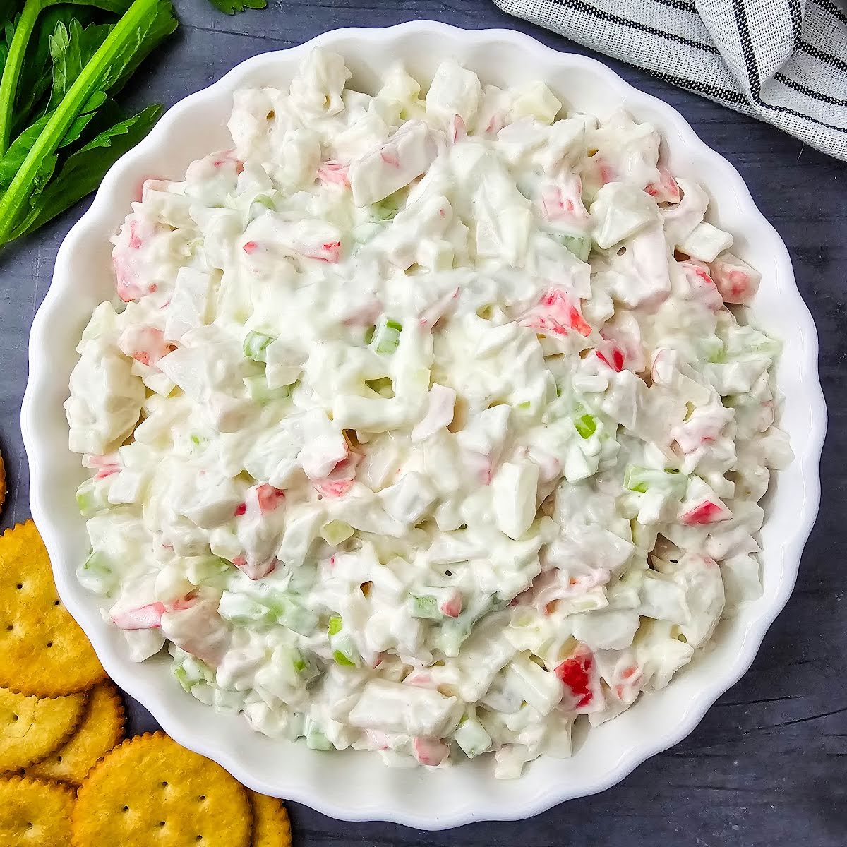 Crab salad in white dish next to crackers.
